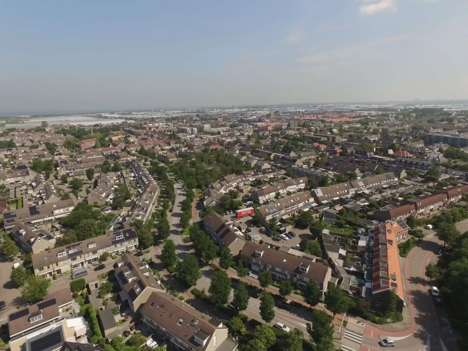 Luchtfoto van een woonwijk met kassen aan de horizon in de regio Westland, Zuid-Holland
