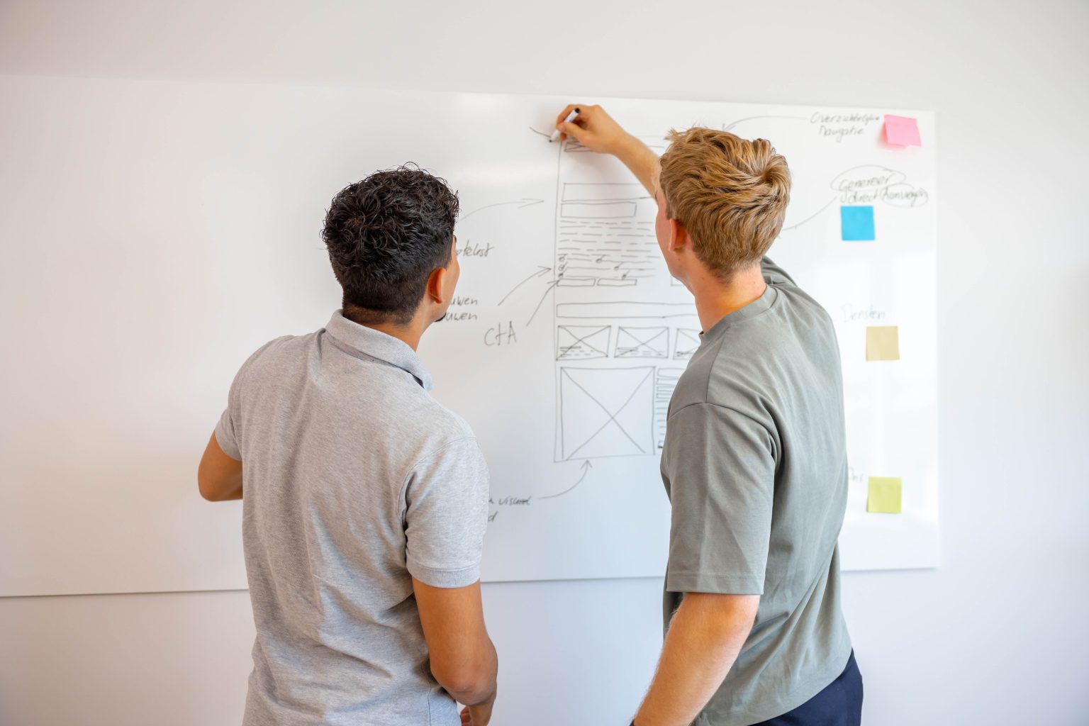 Lars en Jonathan schetsen de structuur van een nieuwe website op het whiteboard