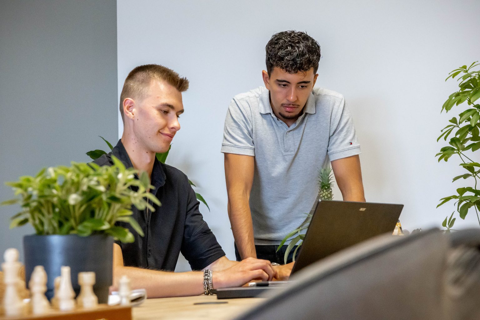 Twee collega's van LarsWebdesign overleggen achter een laptop op kantoor