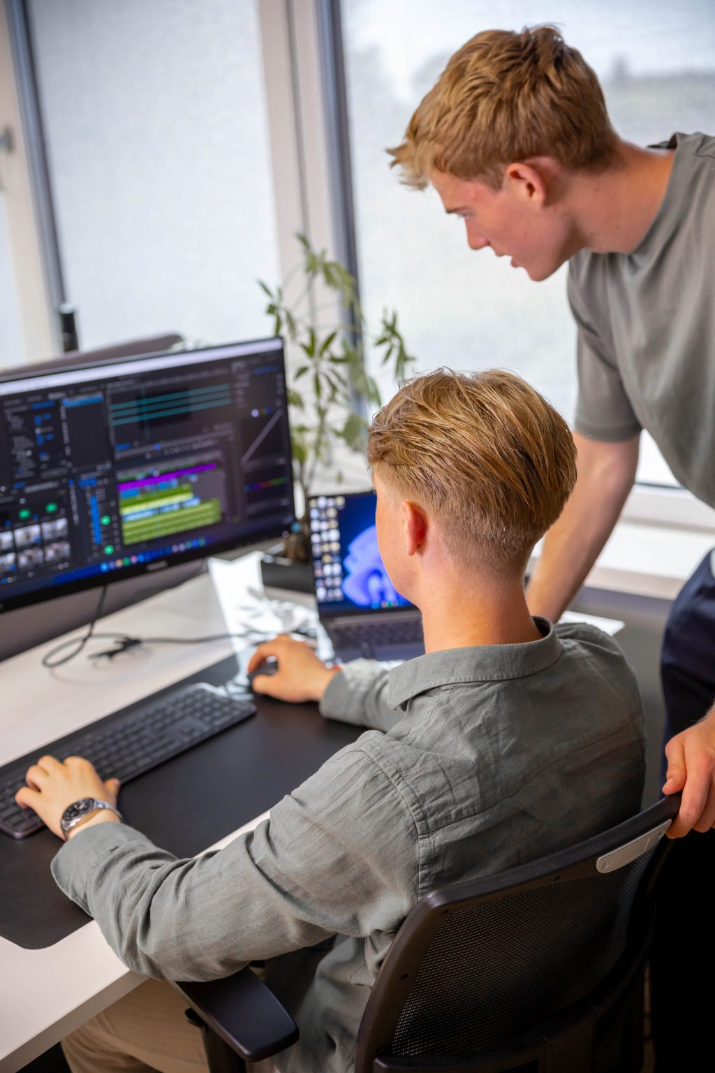 Webdeveloper werkt aan twee schermen aan de techniek van een website, collega kijkt mee